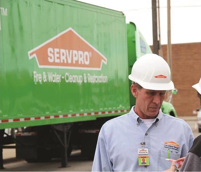 a SERVPRO employee reviewing plans in front of a large SERVPRO trailer truck
