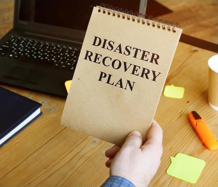 disaster recovery plan being held by a person sitting at desk